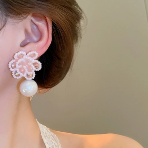 Macro shot of pearl flower drop earrings with pink beads worn on ear for elegant detail