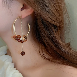 Detailed view of bohemian sandalwood bead earrings with gold C-shape and long metal chain