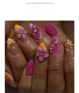 Detailed macro view of almond shaped fake nails with 3D floral and shell decorations