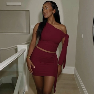 Detail of burgundy one-shoulder long sleeve top and ruched mini skirt set in silky fabric