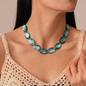 Close-up of a teal oval resin bead necklace with marbled texture on a female model