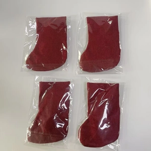 Détail de quatre chaussettes de Noël en toile de jute rouge dans un emballage individuel