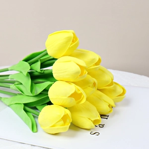 Close-up of yellow PU mini tulips with green leaves against a minimalist background