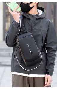 Detail view of black sling bag featuring a side USB charging port and secure combination lock