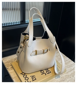 Close-up of white lychee leather bucket bag with golden hardware and wide shoulder strap