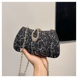 Detail of black evening bag with silver pattern, rhinestone buckle and gold chain strap