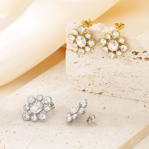 Vintage floral stud earrings with large central crystal on elegant satin background