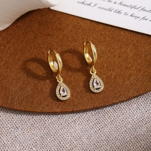 Close-up of gold drop earrings with pear-cut center stone and pave zircon details