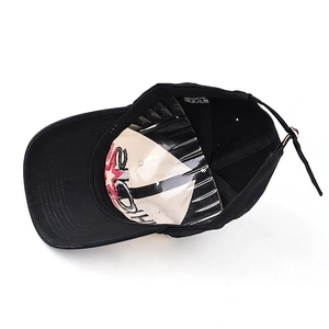 Internal view of black cotton baseball cap showing 100% cotton label and metal buckle
