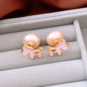 Close-up of pink pony stud earrings with pearls on gray velvet jewelry display