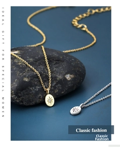 Detail of star engraved oval pendant necklace in gold and silver on black stone