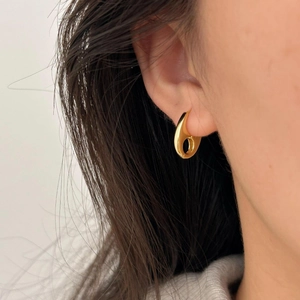 Close-up of minimalist gold polished sterling silver earring worn by a model