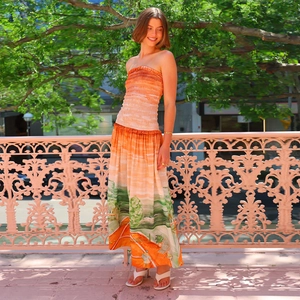 Detail of strapless backless dress with green and orange landscape print in sunlight
