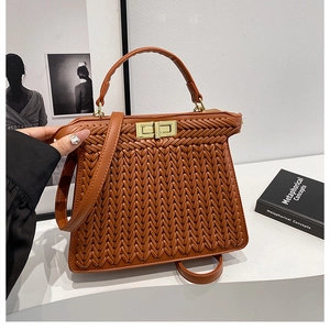 Detail of brown woven PU leather handbag with gold square buckle and adjustable strap
