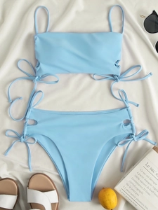 Flat lay of light blue drawstring bikini with summer vacation accessories and decor
