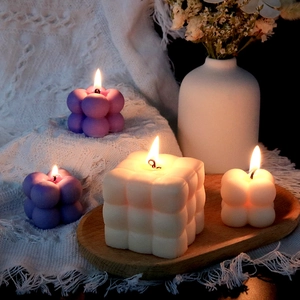 Ambiance cosy avec bougies bulles violettes et cubes blancs allumées sur un plateau bois