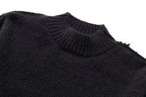 Close-up of black knit sweater featuring a ribbed crew neck and textured fabric weave