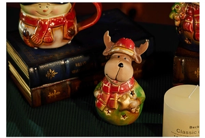 Close-up of a ceramic Christmas reindeer figurine with a star cut-out and a snowman mug