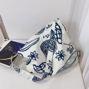 Détail d'un sac cabas en toile avec motif floral et étiquette à côté d'un livre
