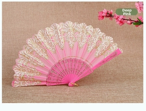 Detail of deep pink folding fan with gold lace patterns and embossed plastic ribs