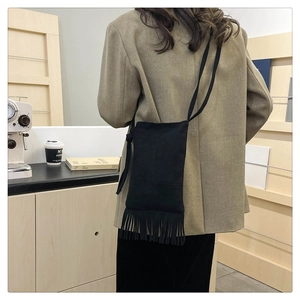 Close-up of a vintage black suede crossbody bag featuring retro tassel edge details