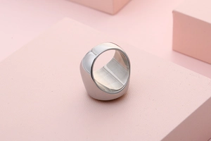 Detailed view of wide silver signet ring with polished finish on geometric pedestal