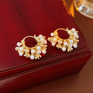 Detail of vintage U-shaped gold earrings with white pearls and crystals on a wood box