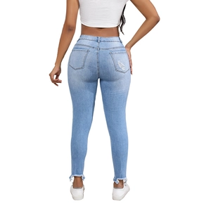 Women's light blue skinny jeans with distressed details and raw hem shown from back view