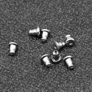 Polished stainless steel bullet earring back stoppers scattered on matte grey background
