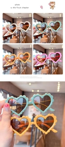 Close-up of heart-shaped kids sunglasses with scalloped edges in candy color tones