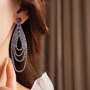 Macro view of purple rhinestone fringe earrings with blue center stone on model