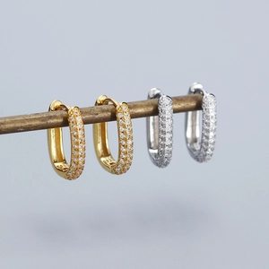 Close-up of gold and silver S925 sterling silver oval hoop earrings with paved cubic zirconia