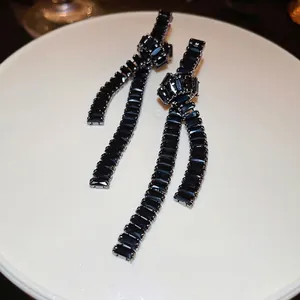 Elegant silver needle knot earrings with black cubic zirconia and long tassels on stand