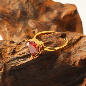 Macro shot of 18k gold plated heart-shaped red zircon ring on natural wood background