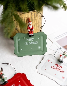 Detail of Christmas metal welcome signs featuring Santa and snowman figurines in a cozy setting