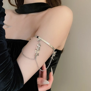 Detailed close-up of a silver butterfly tassel armlet on a black velvet sleeve