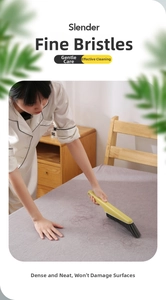 Detail of long-handle cleaning brush removing hair and debris on grey bed sheets
