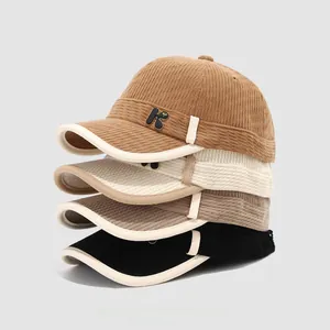 Detailed close-up of corduroy kids' baseball caps in brown, cream, taupe, and black