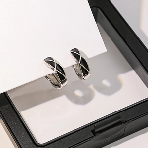 Vue macro de boucles d'oreilles argentées géométriques avec émail noir à motif de damier