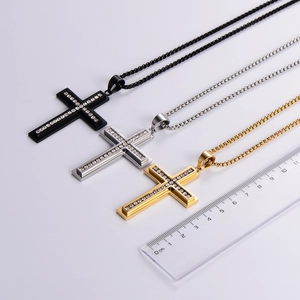 Close-up of diamond-set cross necklaces in black, silver and gold with size reference