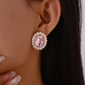 Detail of elegant pink oval gemstone earrings with sparkling diamond halo and gold plating