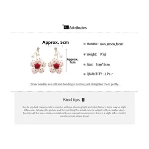 Detailed specs of floral earrings with white polka dots, red pompom, and zircon accents