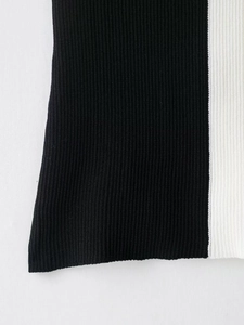 Dettaglio del patchwork verticale bianco e nero sull'orlo in maglia a coste