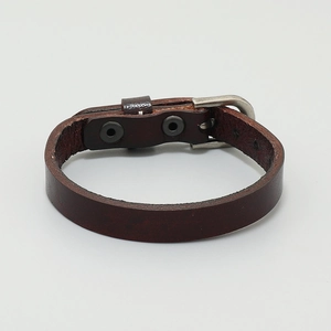 Detail of dark brown leather bracelet featuring adjustable metal buckle and rivets