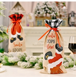 Detail of burlap Santa wine bottle covers with red plaid collars by a fireplace