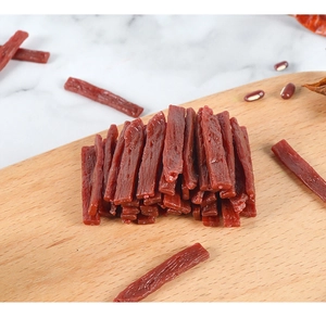 Macro detail of miniature PVC beef jerky model with realistic dried meat texture on wood