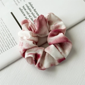 Detail of red and white tie-dye chiffon scrunchie with soft fabric texture on a book