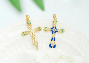 Close-up of gold-plated cross pendants with enamel and zircon details on a ceramic dish