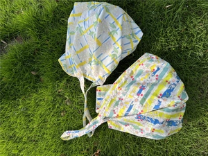 Detailed texture of cotton floral headscarf with ties on green grass background