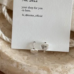 Detailed view of polished S925 sterling silver heart stud earrings on elegant textured card